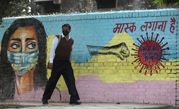 epa08804147 An Indian man passes by a mural on a wall to spread awareness about wearing a protective face mask to avoid spread of novel coronavirus in New Delhi, India, 07 November 2020. According to  ...