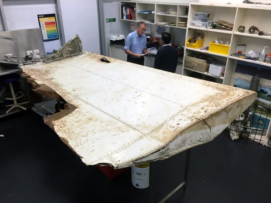 epa05432920 An undated handout picture made available by the Australian Transport Safety Bureau (ATSB) on 20 July 2016 shows Malaysian and Australian investigators examining a piece of aircraft debris ...