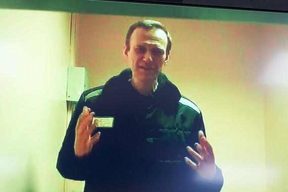 Russian opposition leader Alexei Navalny is seen on a TV screen, as he appears in a video link provided by the Russian Federal Penitentiary Service in a courtroom of the Basmanny Court in Moscow, Russ ...