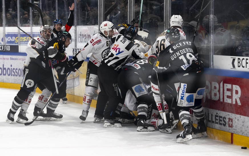 Spieler kaempfen sich beim Eishockey Meisterschaftsspiel der National League A zwischen dem HC Fribourg Gotteron, HCFG, und dem HC Lugano, HCL, am Samstag, 19. Oktober 2024, in der BCF Arena in Fribou ...
