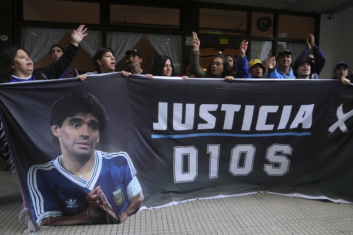 Fans of the late soccer star Diego Maradona hold a banner that reads in Spanish "Justice for God" outside the court where members of the medical team that treated Maradona go on trial for al ...