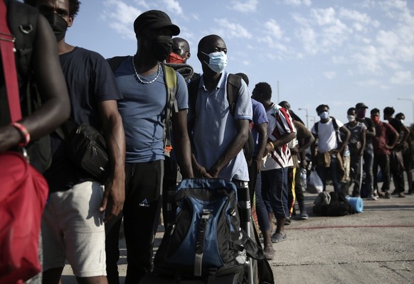 Migrants wait in a queue to enter a temporary camp near Mytilene town, on the northeastern island of Lesbos, Greece, Saturday, Sept. 12, 2020. Greek authorities have been scrambling to find a way to h ...