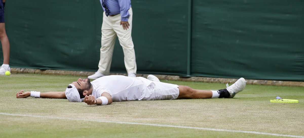 Italy's Matteo Berrettini falls to the ground as he celebrates after beating Argentina's Diego Schwartzman in a Men's singles match during day six of the Wimbledon Tennis Championships  ...