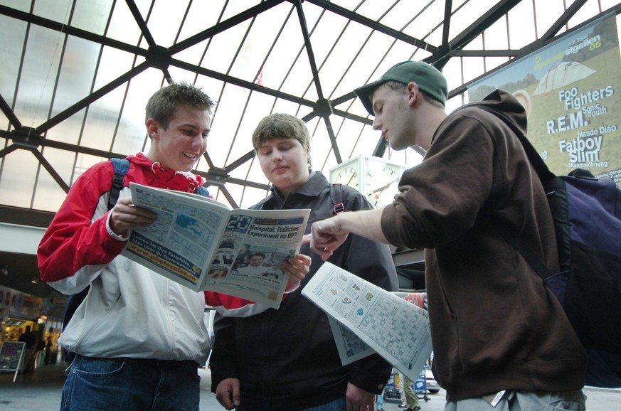 Junge Pendler schauen sich am Montag, 13. Juni 2005, im Hauptbahnhof von St. Gallen die erste St. Galler Ausgabe der Pendlerzeitung "20minuten" an. Zwei Regionalseiten sind fuer Themen aus d ...
