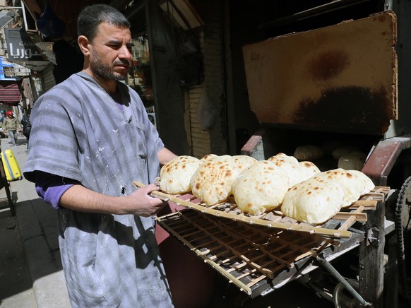 epa09826544 An Egyptian baker arranges bread at a bakery in Cairo, Egypt, 15 March 2022. The Egyptian government said the country is expecting in the coming days a shipment of about 126,000 tons of wh ...