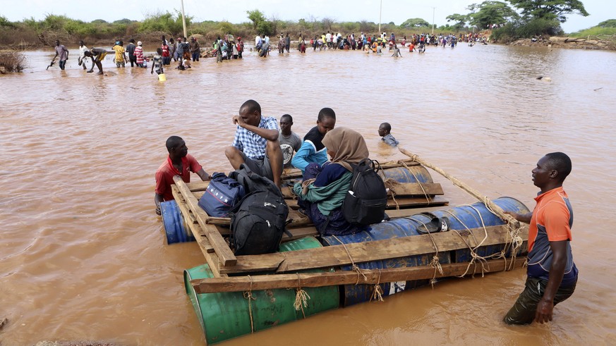 People cross a flooded area on makeshift floating tanks at Mororo, border of Tana River and Garissa counties, North Eastern Kenya, Thursday, Nov. 30, 2023. Kenya&#039;s government is urging people liv ...
