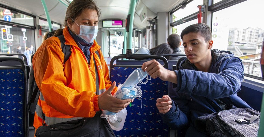 epa08417813 A member staff of the Transports publics genevois, TPG, (Geneva Public Transport), distributes protective face masks as a preventive mesure against the spread the coronavirus COVID-19 to p ...