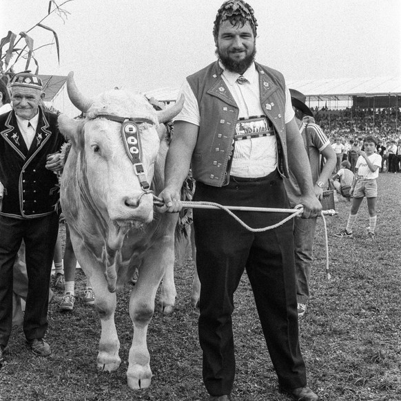 Ernst Schlaepfer posiert als Schwingerkoenig mit einem jungen Stier, seinem Preis am eidgenoessischen Schwingfest am 21. August 1983 in Langenthal. (KEYSTONE/Str)