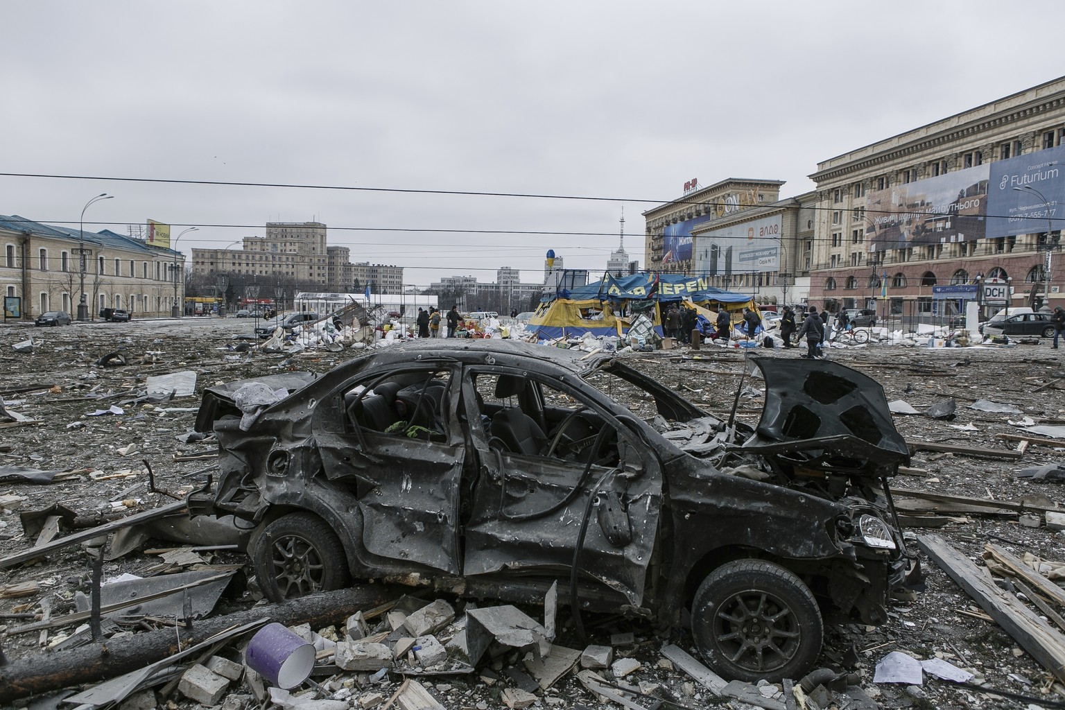 A damaged car sits at the central square following shelling of the City Hall building in Kharkiv, Ukraine, Tuesday, March 1, 2022.(AP Photo/Pavel Dorogoy)