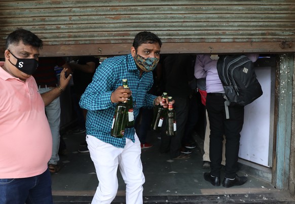 epa09145167 A man carries bottles of drinks after buying alcohol at a liquor store as a one week curfew is announced in New Delhi, India, 19 April 2021. One week curfew is imposed to curb the extreme  ...