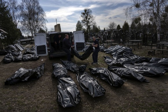 Cemetery workers unload bodies of killed civilians from a van in the cemetery in Bucha, outskirts of Kyiv, Ukraine, Thursday, April 7, 2022. (AP Photo/Rodrigo Abd)