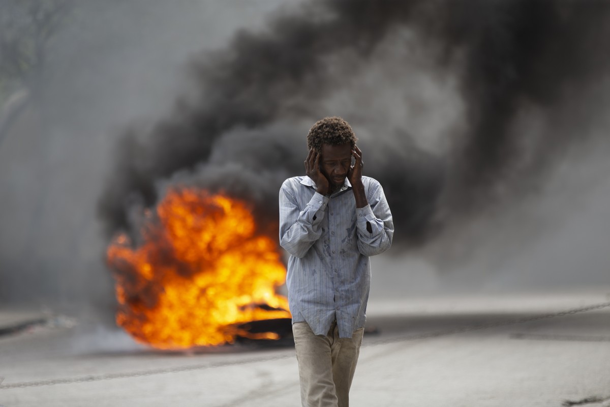 A man walks past a burning barricade during a protest over the death of journalist Romelson Vilsaint, in Port-au-Prince, Haiti, Sunday, Oct. 30, 2022. Vilsaint died Sunday after being shot in the head ...