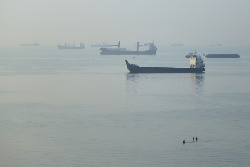 KEYPIX - People wade in the water as cargo ships are anchored in the Strait of Hormuz off Bandar Abbas, Iran, early Monday, Sept. 28, 2026. (KEYSTONE/Amirhosein Khorgooi/ISNA via AP)