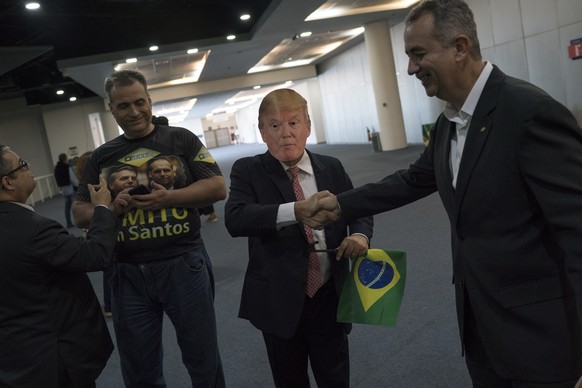 A supporter of Brazil&#039;s presidential candidate Jair Bolsonaro, wearing a mask of President Donald Trump, arrives to the National Social Liberal Party convention where Bolsonaro is to accept the n ...