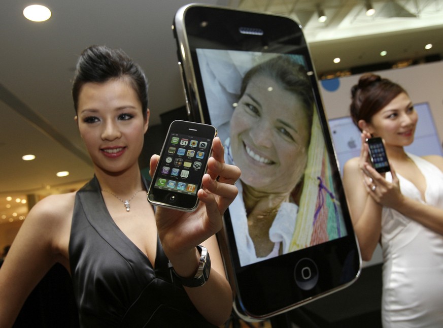 FILE - In this July 11, 2008 file photo, models hold the new iPhones during the first day of the release in Hong Kong. Apple Inc. partner China Unicom Ltd. has sold 5,000 iPhones since the smart phone ...