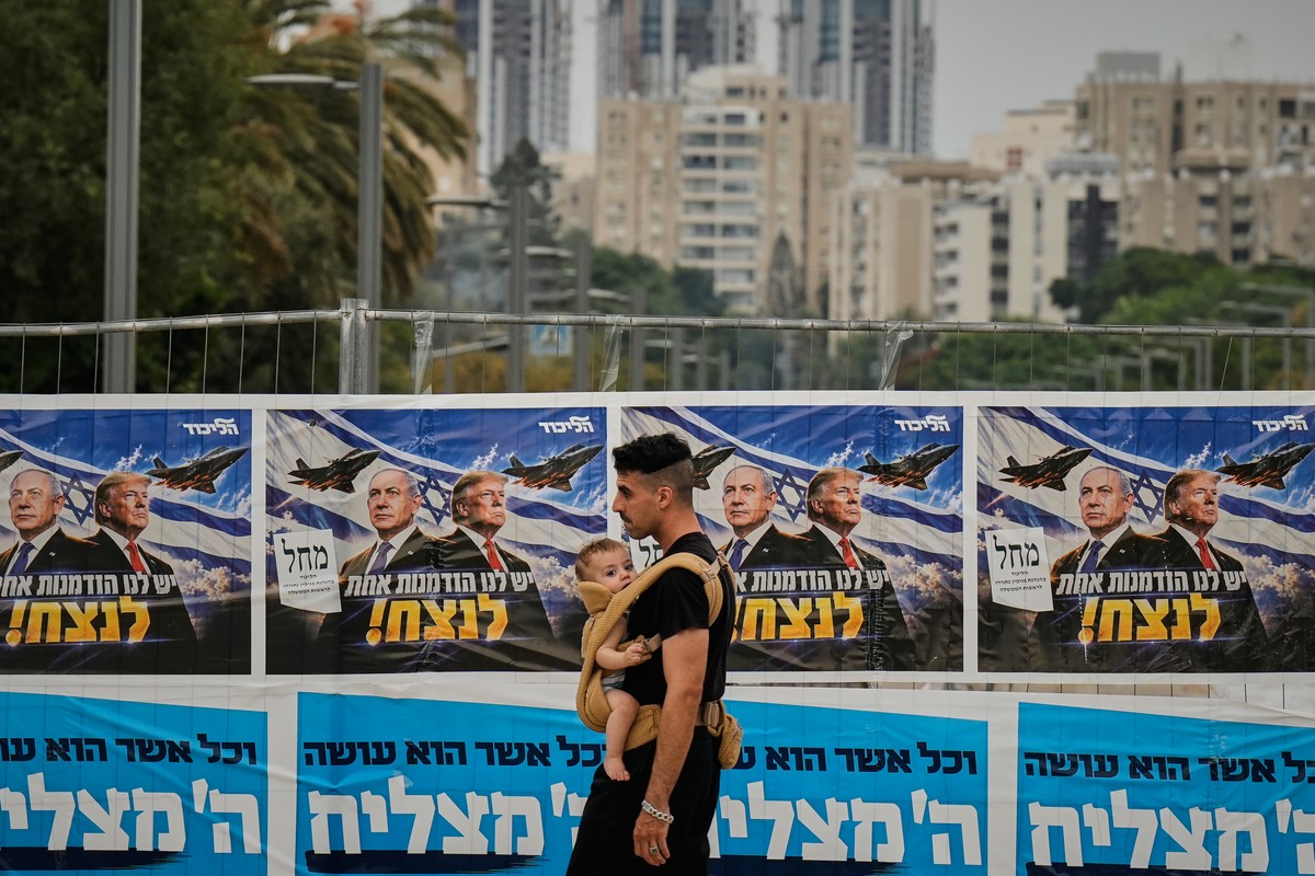 A man walks past a Likud Party campaign banner featuring Israeli Prime Minister Benjamin Netanyahu and U.S. President Donald Trump, with a Hebrew message reading, "We have one opportunity to win, ...