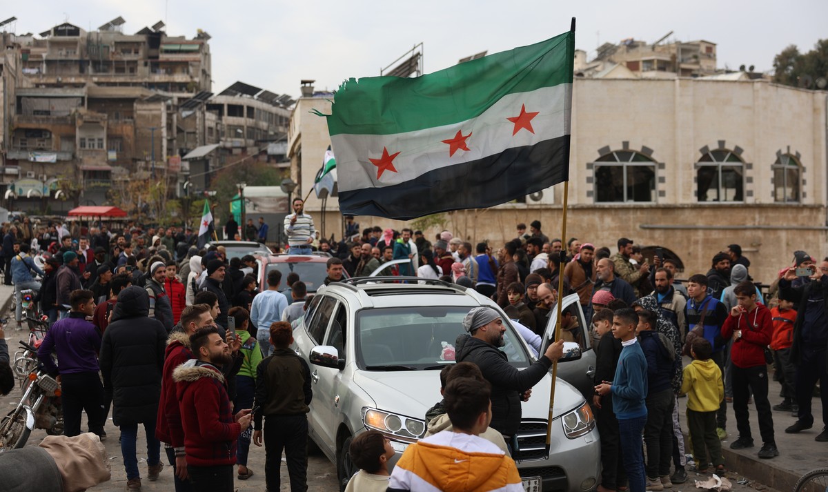 epa11762428 People wave a Syrian opposition flag after opposition fighters took control of the city of Hama, Syria, 07 December 2024. Syrian opposition forces, led by the Islamist militant group Hayat ...