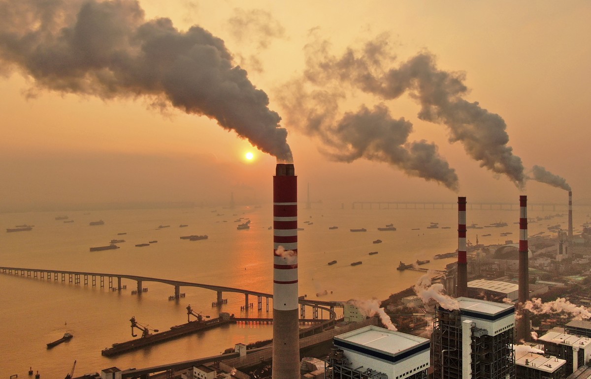 The sun sets near a coal-fired power plant on the Yangtze River in Nantong in eastern China's Jiangsu province on Dec. 12, 2018. Chinese power companies bid for credits to emit carbon dioxide and ...