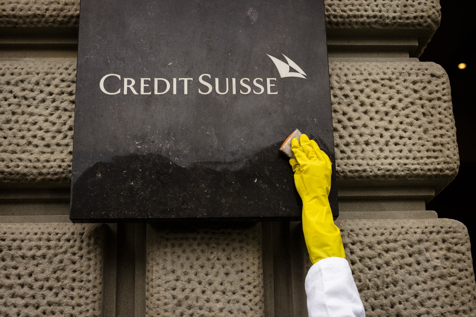 An activist of Scientist Rebellion cleans symbolically.the entrance of the Swiss Bank Credit Suisse at Paradeplatz during a protest against fossil fuel investments, in Zurich, Switzerland on Wednesday ...