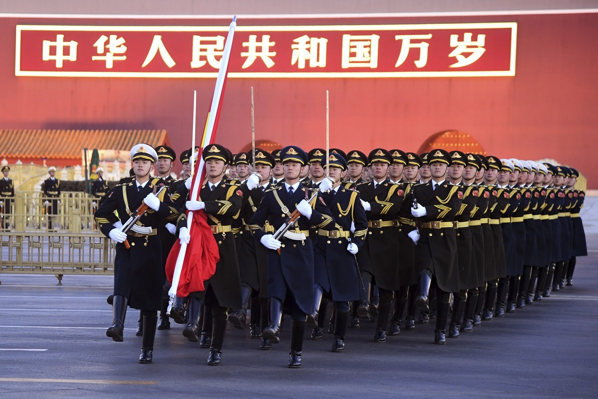 In this photo released by Xinhua News Agency, a Chinese honor guard marches with the national flag near the words "Long Live the People's Republic of China" on Tiananmen Gate in Beijing ...