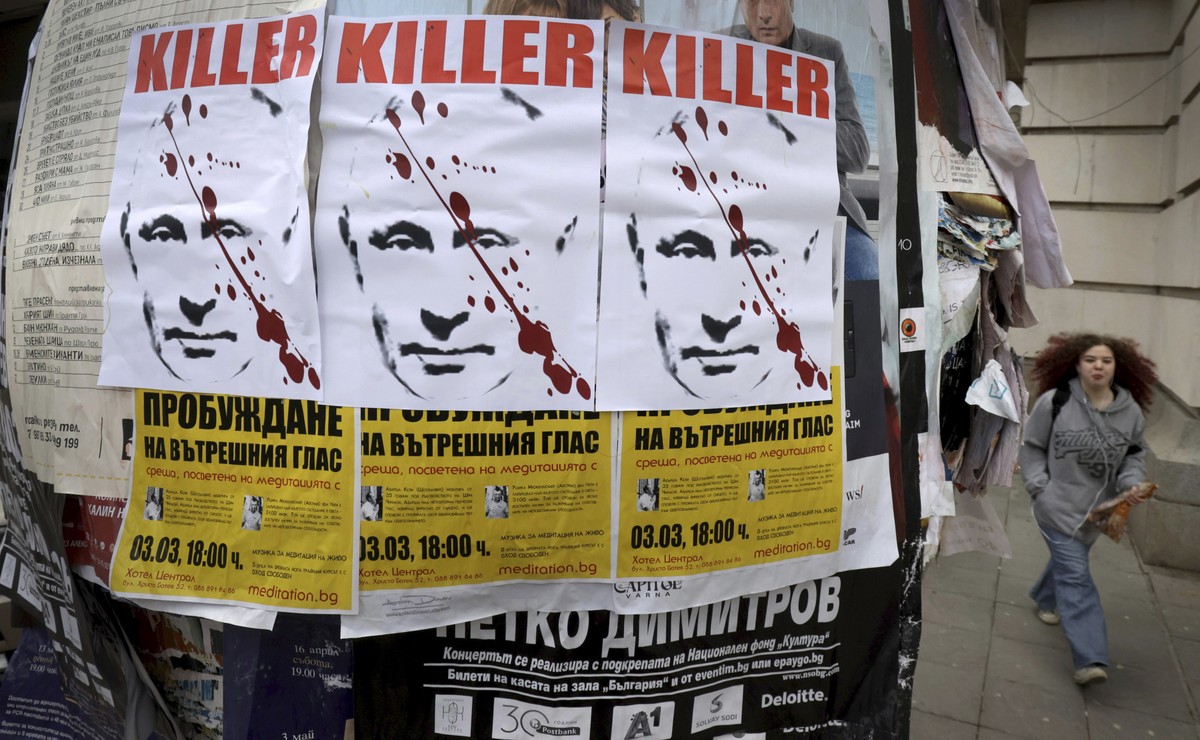 A woman passes by posters depicting Russian President Vladimir Putin with a sign "Killer" seen in downtown Sofia Thursday, Feb. 24, 2022. The posters appeared on the day Russia started milit ...