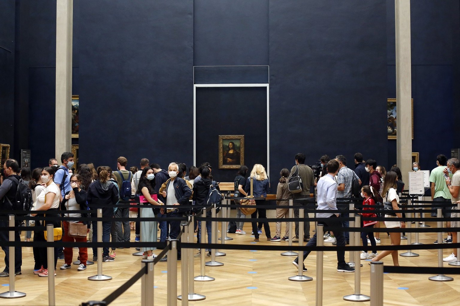 Visitors wait to see the Leonardo da Vinci&#039;s painting Mona Lisa, in Paris, Monday, July 6, 2020. The home of the world&#039;s most famous portrait, the Louvre Museum in Paris, reopened Monday aft ...
