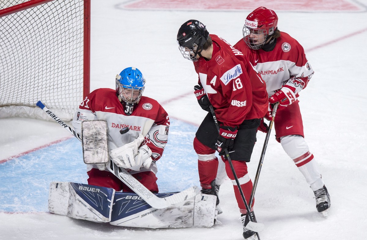 Denmark goaltender Lasse Petersen stops the puck in front of Switzerland's Nico Hischier and Denark's Oliver Larsen during the first period of a World Junior hockey tournament game Friday, D ...