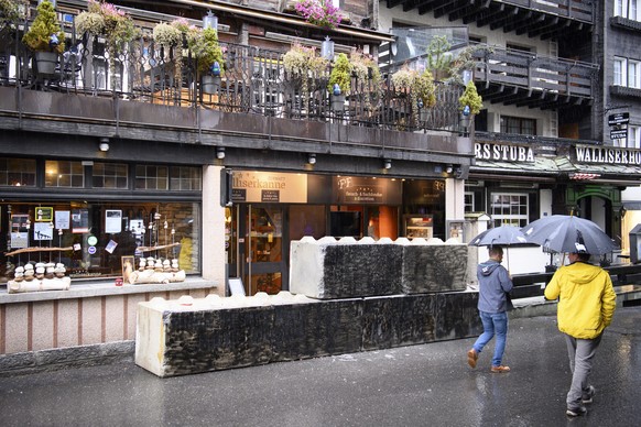 epa09557256 Peoples pass in front of concrete blocks blocked the entrance of the restaurant &quot;Walliserkanne&quot; after the restaurant was closed and the owners were arrested by the police for not ...