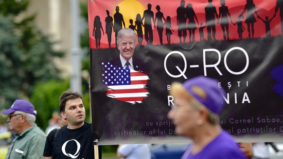 Romanian supporters of QAnon take part in a rally against the government&#039;s measures to prevent the spread of COVID-19 infections, like wearing a face mask, in Bucharest, Romania, Monday, Aug. 10, ...