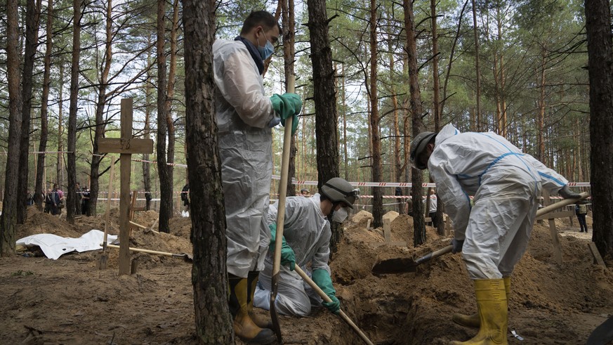 Emergency workers dig into a grave of a civilian during an exhumation in the recently retaken area of Izium, Ukraine, Saturday, Sept. 17, 2022. Ukrainian authorities discovered a mass burial site near ...