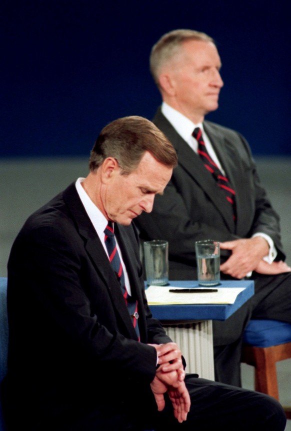 FILE - In this Oct. 15, 1992, file photo President George H.W. Bush looks at his watch during the 1992 presidential campaign debate with other candidates, Independent Ross Perot, top, and Democrat Bil ...