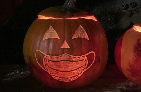 A Halloween pumpkin carved to incorporate a COVID-19 surgical mask is displayed at a home, Sunday, Oct. 31, 2021, in the South Capitol neighborhood of Olympia, Wash. (AP Photo/Ted S. Warren)