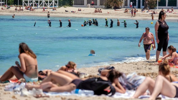 epa08410608 People take advantage of the beautiful day with sunbathing and swimming in the sea on Mondello beach, a long sandy coast, in Palermo, Italy, 08 May 2020. The Italian government is graduall ...