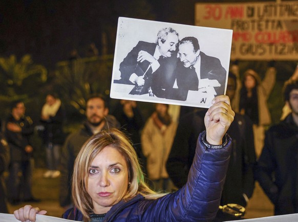 A woman displays a photograph that became iconic in Italy and shows top anti-mafia prosecutors Giovanni Falcone, left, and Paolo Borsellino, during a demonstration in the streets of Palermo, Sicily, I ...