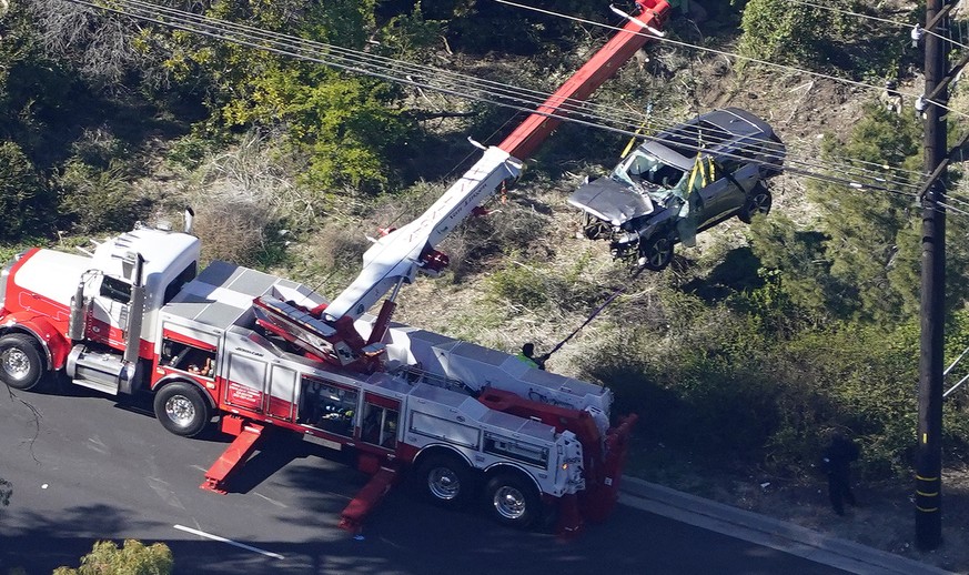 Workers move a vehicle after a rollover accident involving golfer Tiger Woods Tuesday, Feb. 23, 2021, in Rancho Palos Verdes, Calif., a suburb of Los Angeles.. Woods suffered leg injuries in the one-c ...