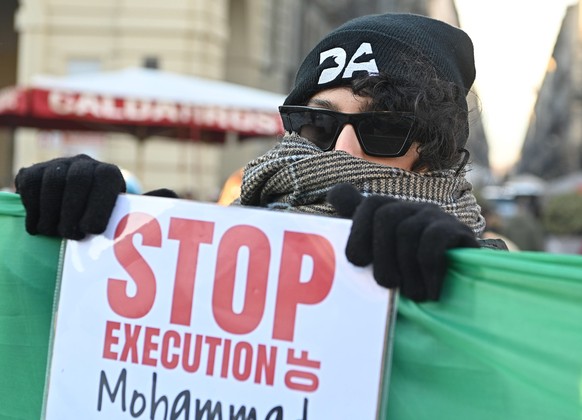 epa10370534 A protester holds a sign as people attend a demonstration against Iran's regime, organized by the Iranian community, in Turin, Italy, December 17, 2022, following the conviction of Iran...