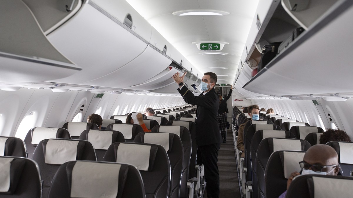epa08486912 A cabin crew member of Swiss International Air Lines, wearing a face mask, prepares the aircraft prior to departure to London at the Geneva Airport, in Geneva, Switzerland, 15 June 2020. F ...