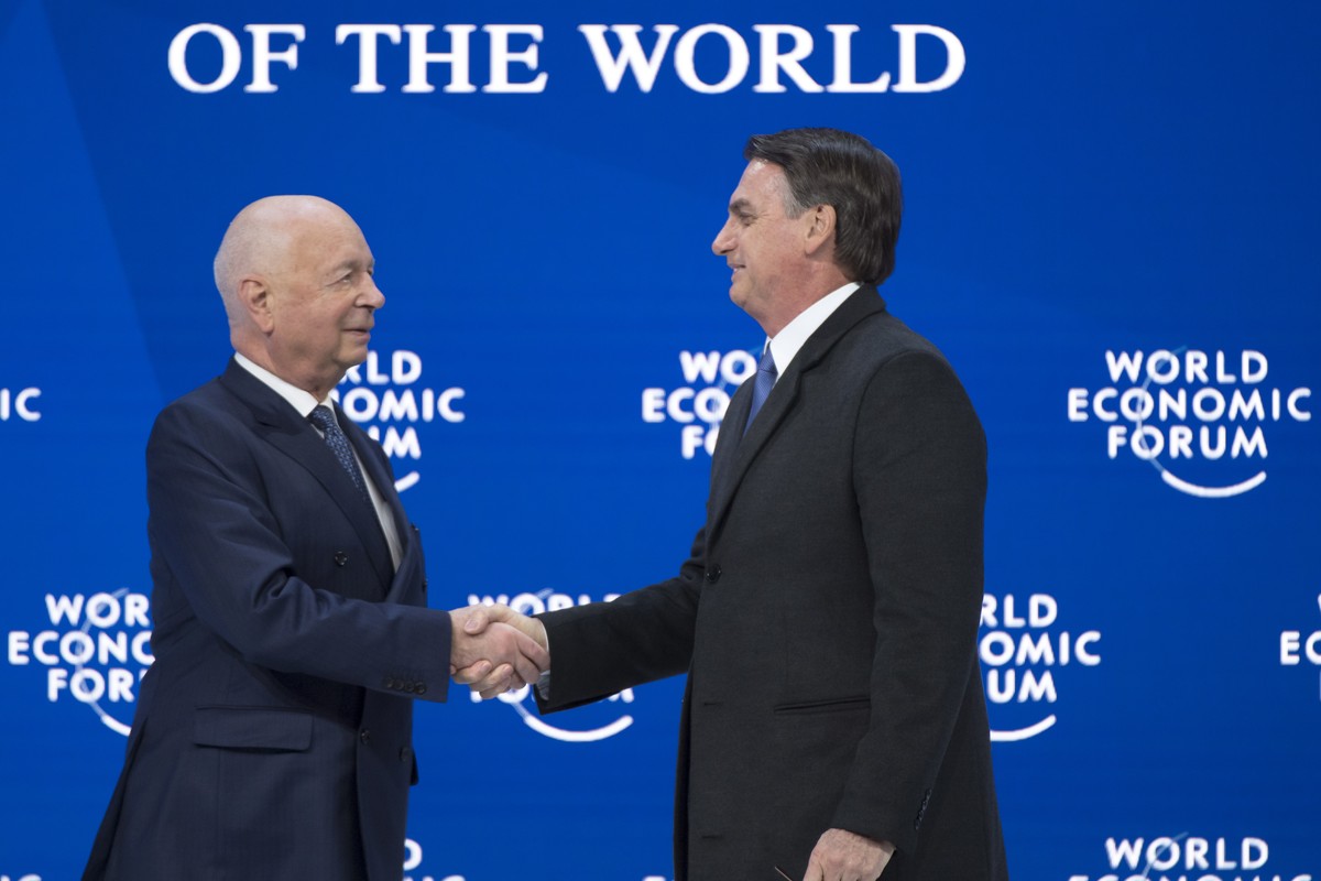 epa07309443 Brazil's President Jair Bolsonaro, (R), shakes hands with German Klaus Schwab, (L), Founder and Executive Chairman of the World Economic Forum, WEF, during a plenary session in the Co ...