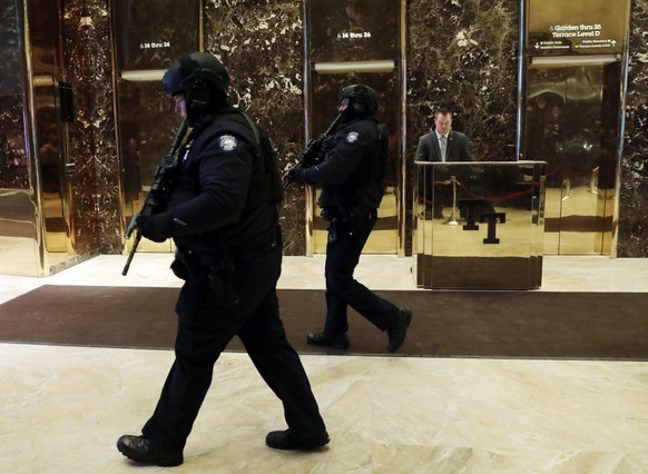 epa05705534 New York City police officers patrol the lobby of Trump Tower in New York, New York, USA, 08 January 2017. President-elect Donald Trump will be sworn in as the 45th President of the United ...