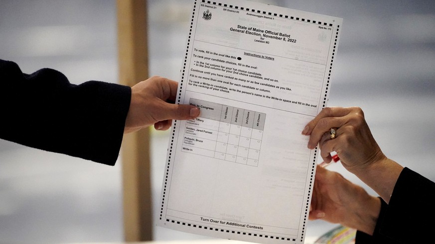 A clerk hands a ballot to a voter on Election Day, Tuesday, Nov. 8, 2022, in Lewiston, Maine. The state of Maine uses a ranked choice voting system for some of its election races. (AP Photo/Robert F.  ...