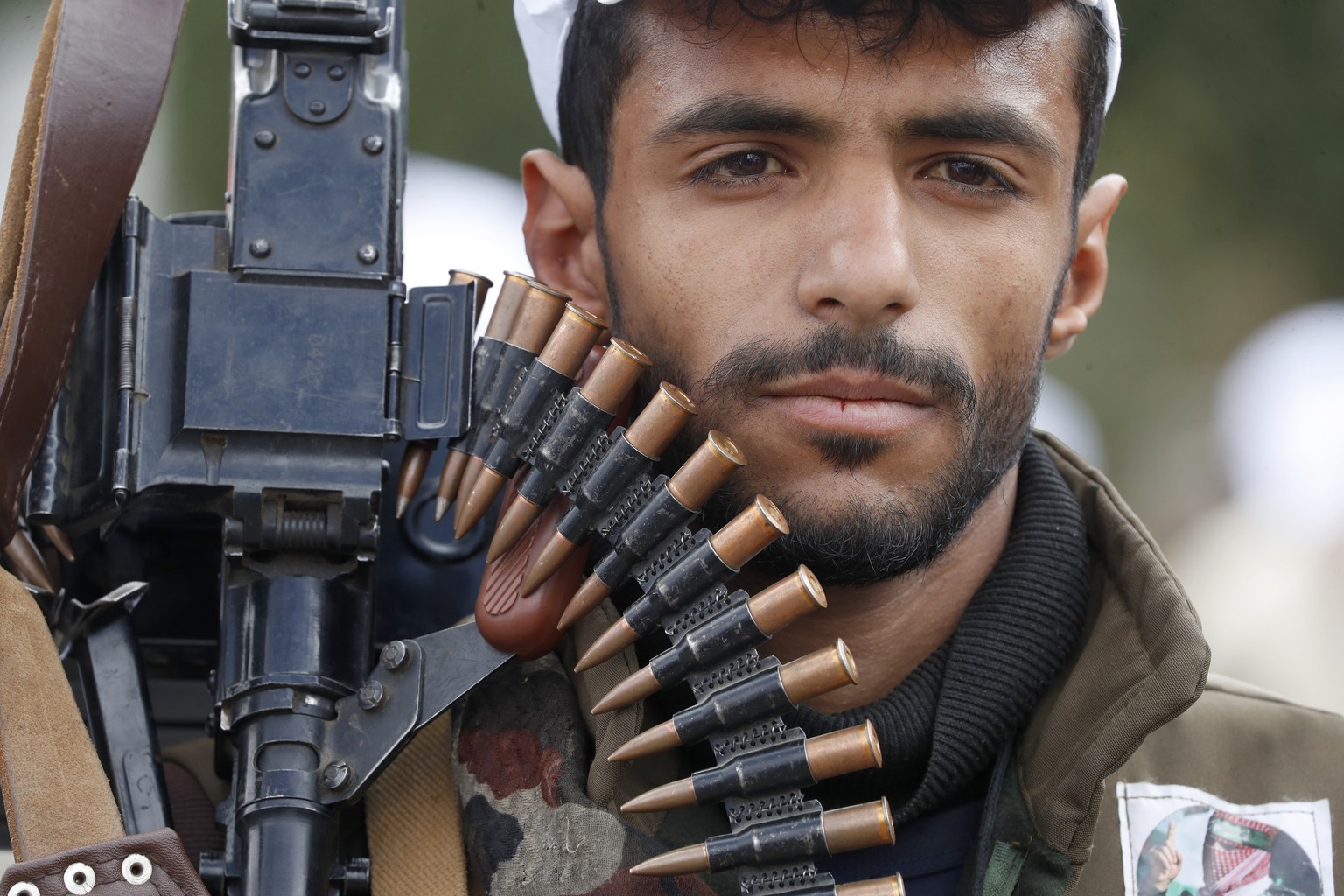 epaselect epa11137091 A new Houthi recruit carries a machine gun with ammunition belt during a gathering to show defiance against the US-British strikes on Houthi positions, in Sana&#039;a, Yemen, 08  ...
