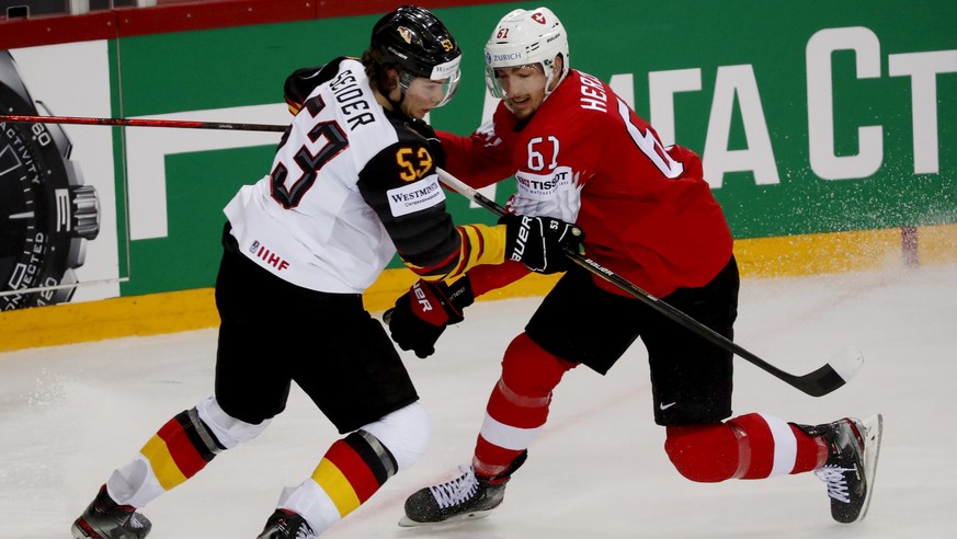 epa09245373 Fabrice Herzog (R) of Switzerland in action against Moritz Seider (L) of Germany during the IIHF Ice Hockey World Championship 2021 quarter final match between Switzerland and Germany at t ...