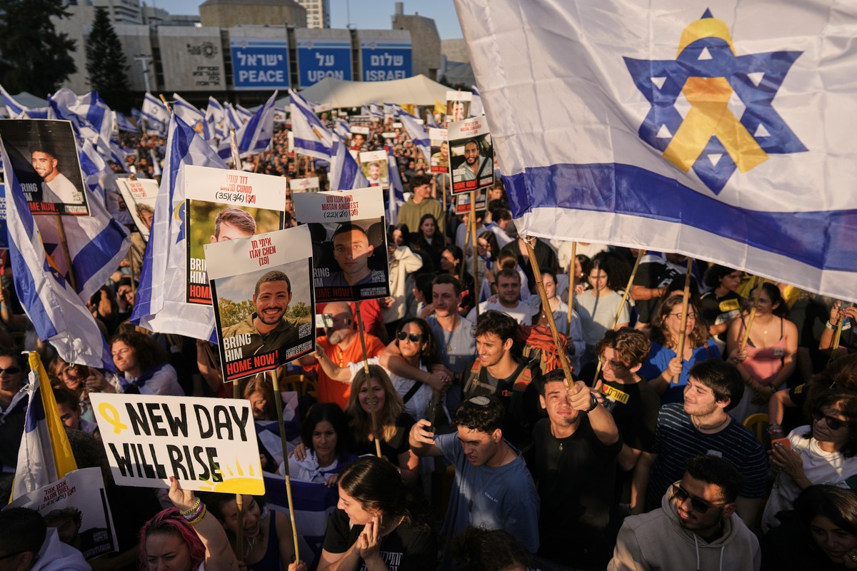 People react as they gather to watch a live broadcast of Israeli hostages released from Gaza at a plaza known as hostages square in Tel Aviv, Israel, Monday, Oct. 13, 2025. The release took place as p ...