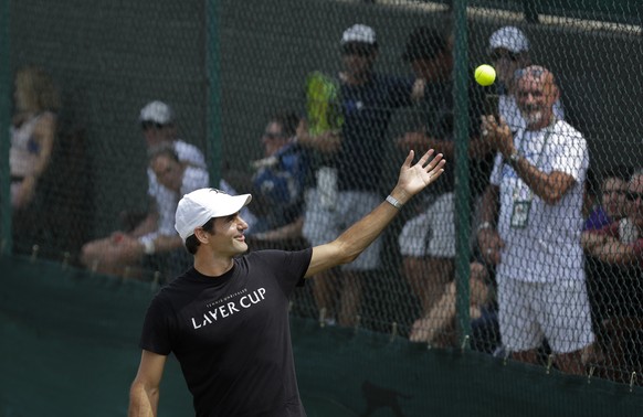 Roger Federer of Switzerland laughs as a spectator returns the ball as he practices ahead of the start of the Wimbledon Tennis Championships in London, Sunday, July 1, 2018. The Championships will sta ...