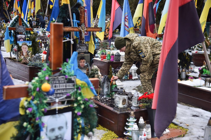 Burial of Ukrainian soldiers at the Lychakiv cemetery in Lviv, Ukraine - 02 Feb 2024 A military cadet places a candle on the grave of a Ukrainian soldier who died in the Russian-Ukrainian war and was  ...