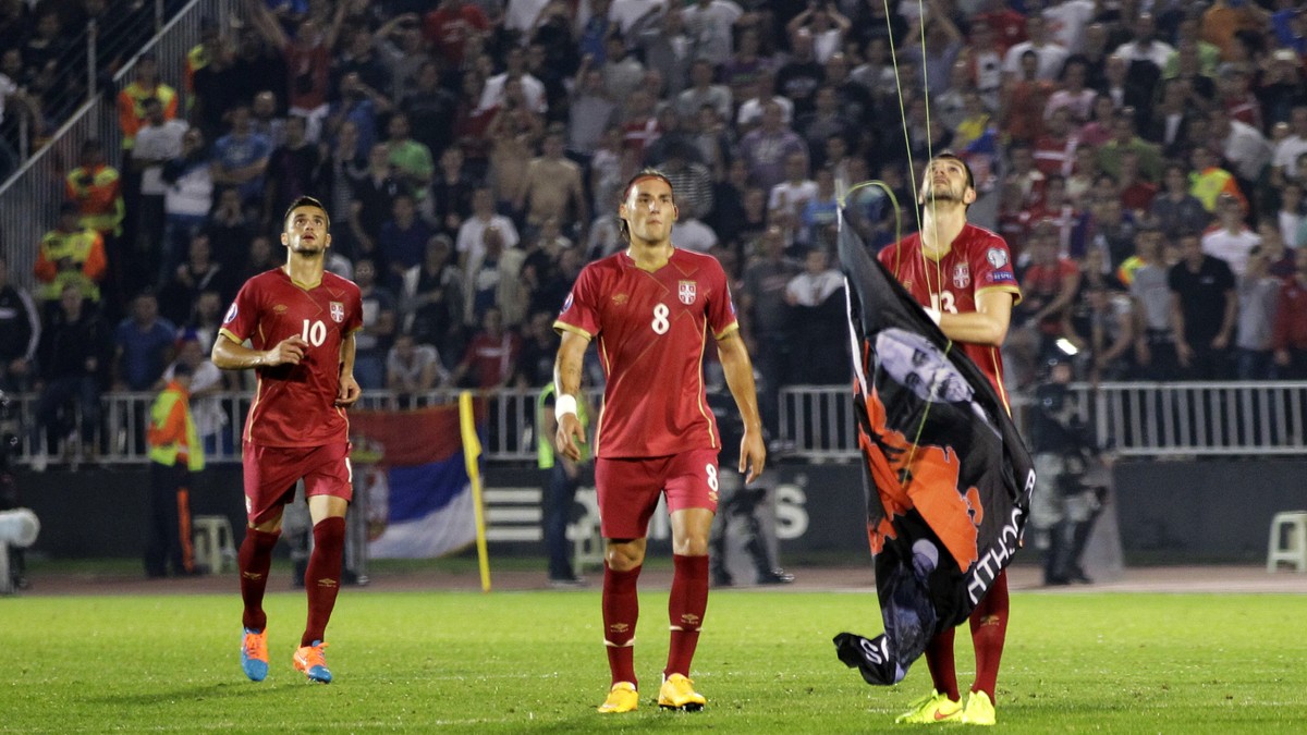 FILE - In this file photo dated Tuesday, Oct. 14, 2014, Serbia's Stefan Mitrovic grabs a banner containing the Albanian flag attached to a drone flying above the pitch during the Euro 2016 Group  ...