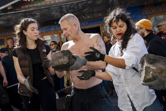 epa11263004 Residents of the free village Christiania jointly dig up the cobblestones at Pusher Street in Copenhagen, Denmark, 06 April 2024. Christiania residents carried out the action in cooperatio ...