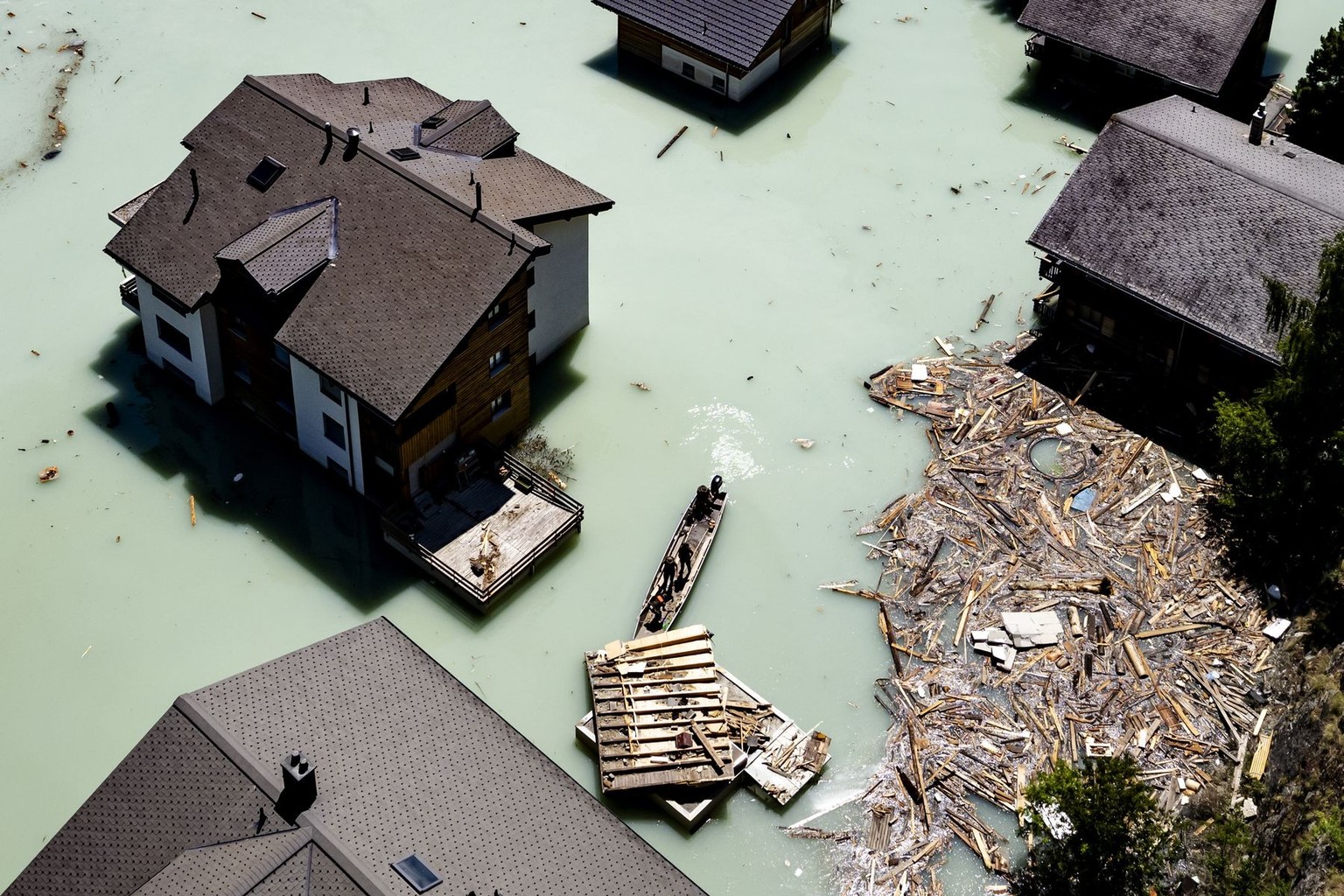 Une vue aerienne montre une barque qui navigue, sur le lac forme apres l'eboulement, avec des militaires de l'Armee suisse qui enlevent les debris le mardi 24 juin 2025 a Blatten dans le Loe ...