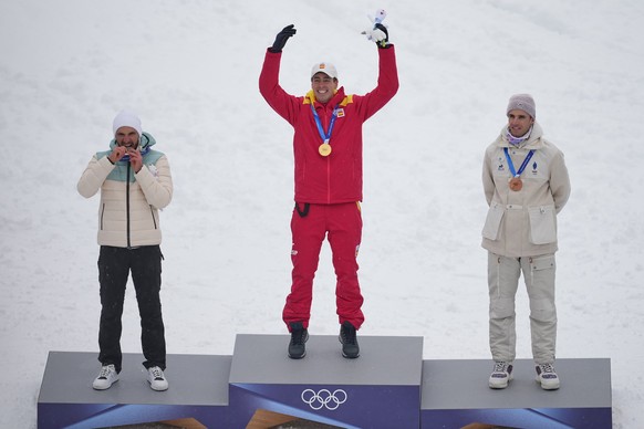 Spain's Oriol Cardona Coll, center, celebrates winning the gold medal in a ski mountaineering men's sprint final, with silver medalist Individual Neutral Athlete Nikita Filippov, left, and b ...