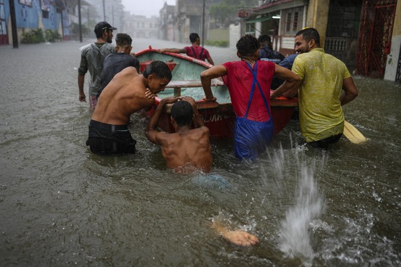 Volunteers push a boat through a street flooded by heavy rains, to go and rescue a neighbor who is unable to leave his home on his own, in Havana, Cuba, Friday, June 3, 2022. Heavy rains have drenched ...